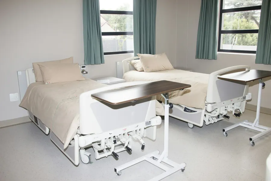 Lits médicalisés blancs dans une chambre claire près d'une fenêtre