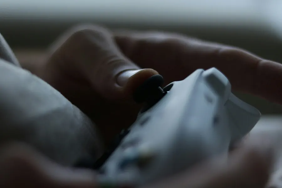 Main qui tient une télécommande générique, pas clairement un lit médicalisé