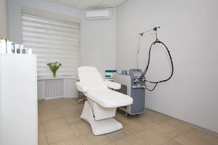 Salle de soins claire, fauteuil d'examen, murs crème, lumière du jour, aucun patient