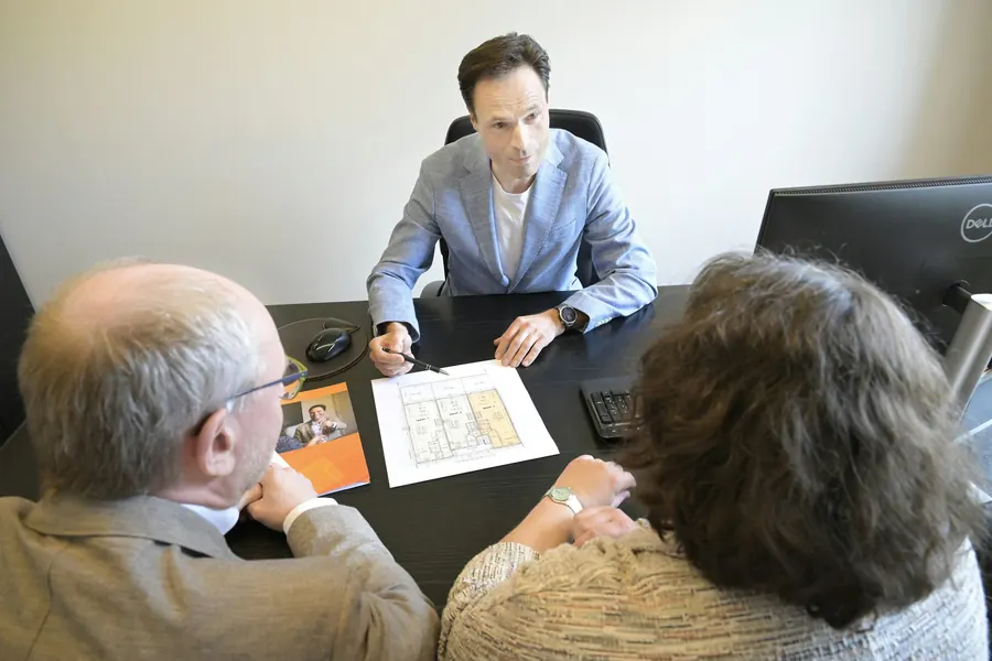 Conseiller qui présente un document à un couple de retraités, dans un bureau