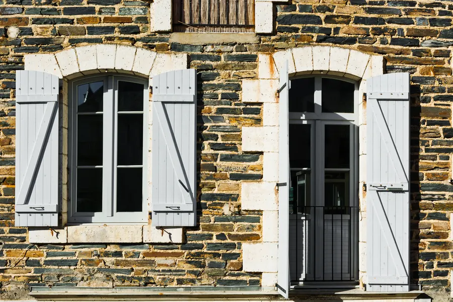 Façade d'une maison de ville en pierre calcaire, porte en bois peinte, plaque de l'office, lumière douce du matin