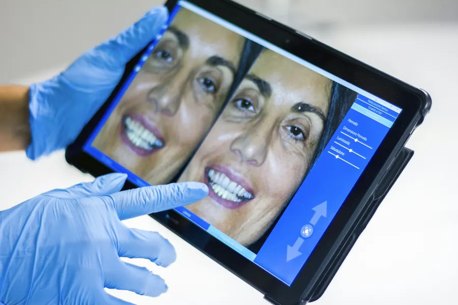 Mains gantées montrant une simulation dentaire numérique sur tablette