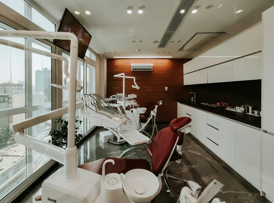 Espace de soins ouvert avec trois fauteuils, grandes fenêtres, touches de couleur, sans patient