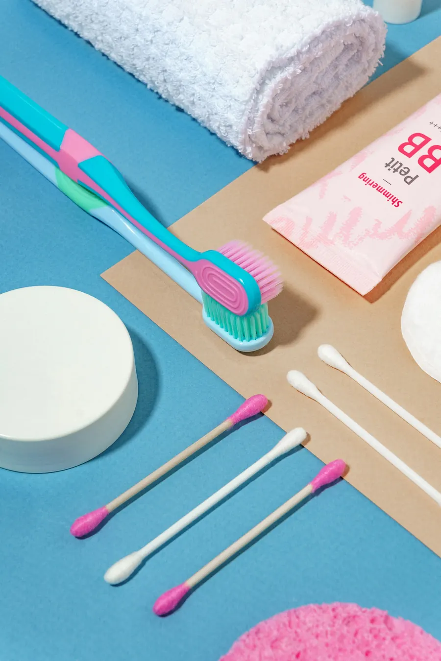 Trousse d'entretien posée à plat : brosse de voyage, brossettes, cire, miroir, sur fond coloré