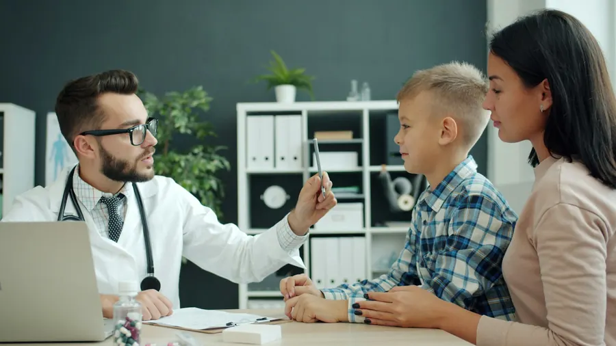 Médecin examinant un garçon en présence de sa mère, sans modèle dentaire