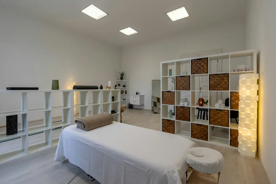 Salle de consultation apaisante : table de soin, bois clair, lin, plante, lumière naturelle, personne
