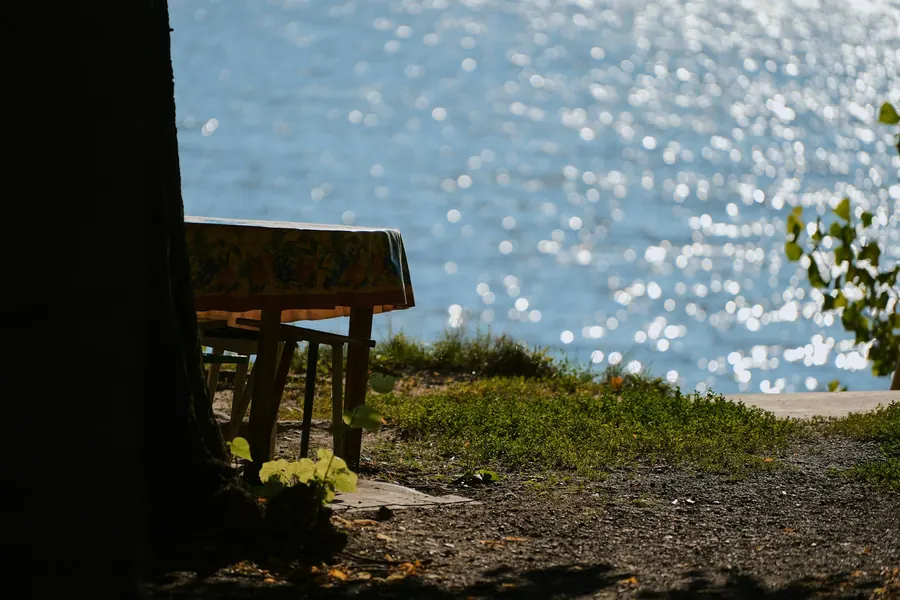 Table en bois près de l'eau scintillante, cabane à l'ombre