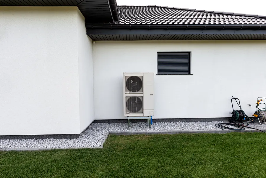 Unité extérieure de pompe à chaleur contre une maison en pierre, campagne de bocage