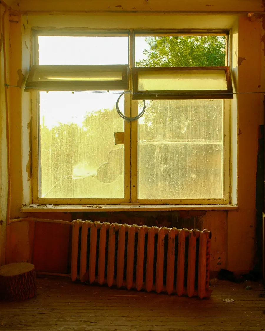 Radiateur en fonte ancien sous une fenêtre, mur de pierre