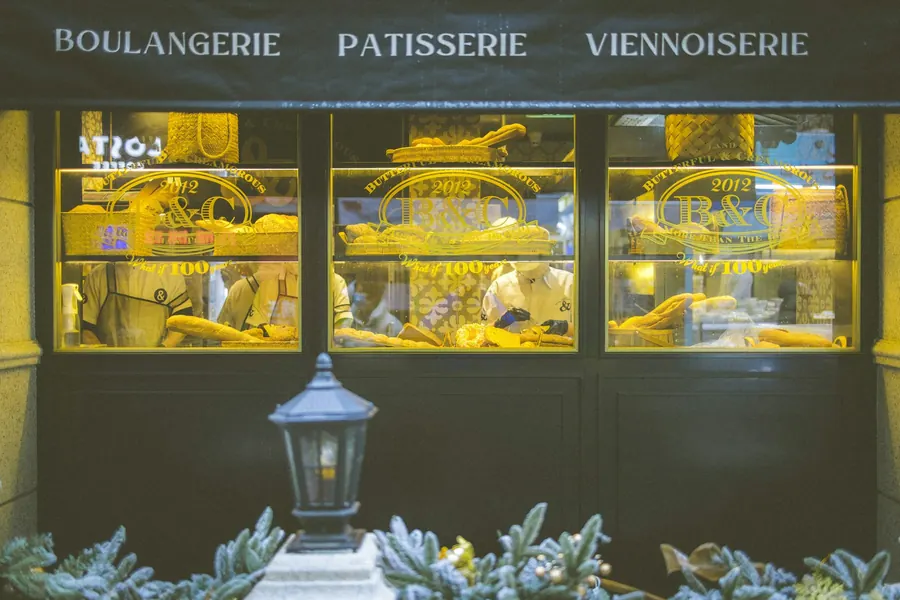 Devanture de pâtisserie dans une rue ancienne en tuffeau et ardoise, vitrine éclairée