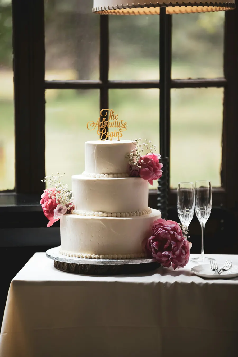 Gâteau de mariage à trois étages dans une pièce sombre, fleurs roses
