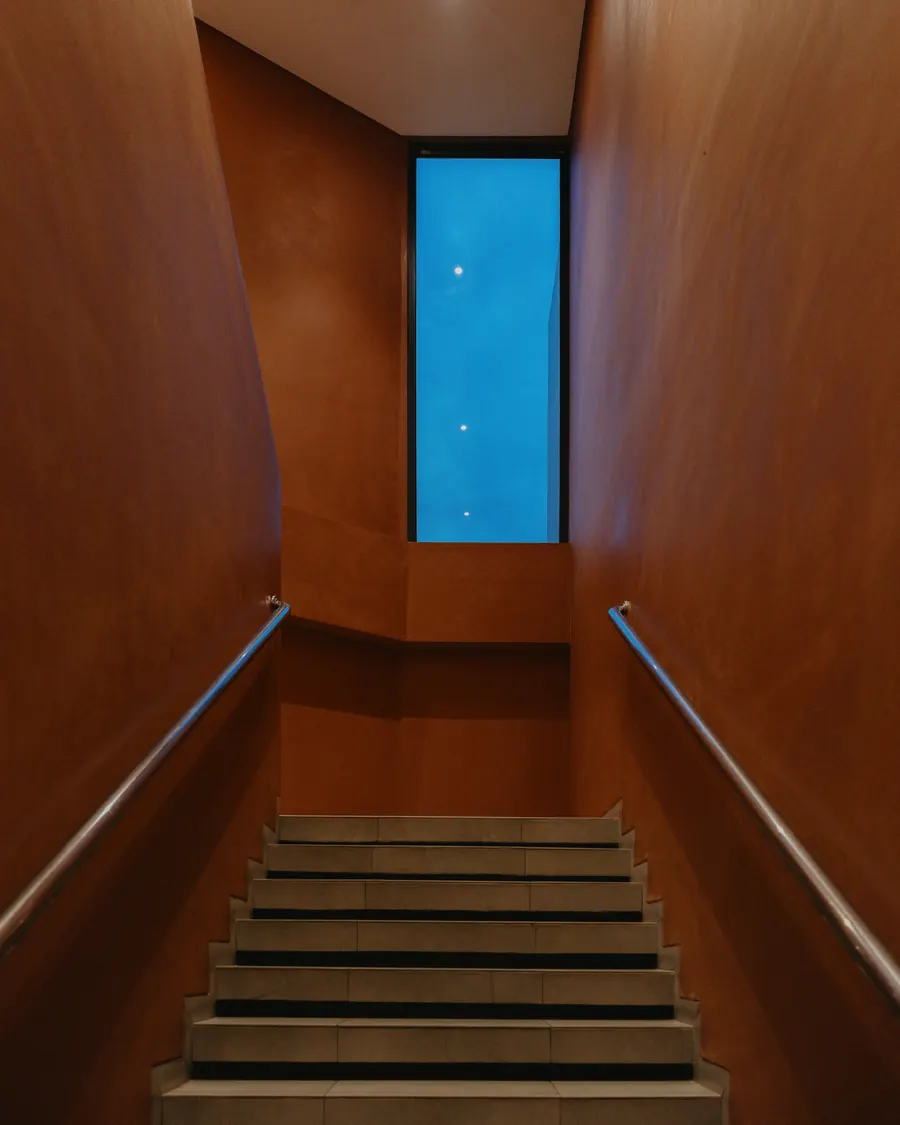 Cage d'escalier repeinte en brun uni, lumière naturelle d'une fenêtre