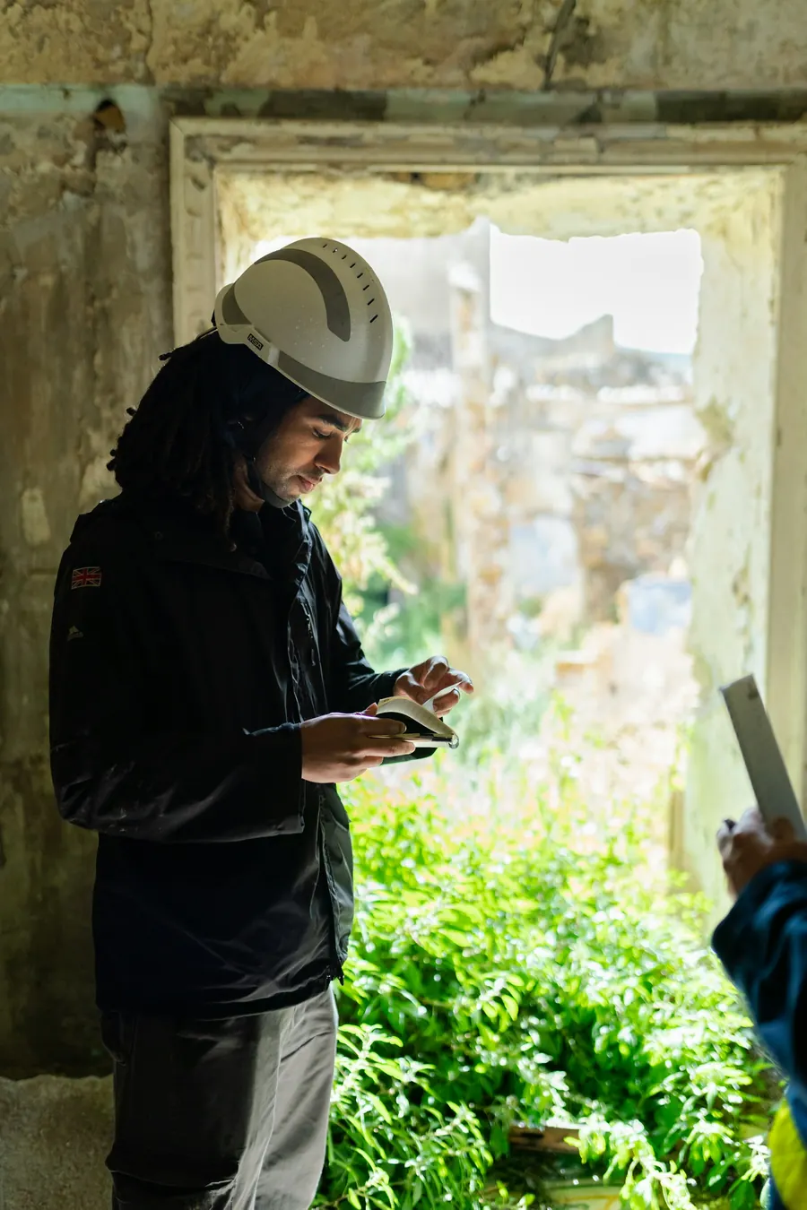 Ingénieure avec une tablette au pied d'un bâtiment, relevé de toiture