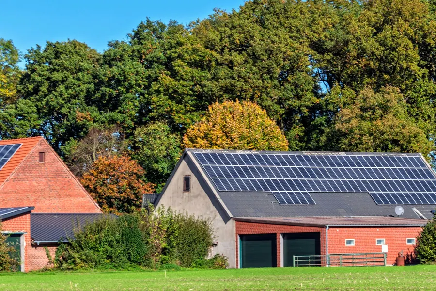 Long bâtiment agricole couvert de panneaux solaires, campagne à l'automne