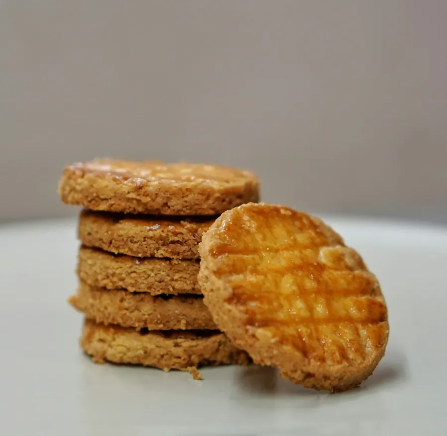 Palets pur beurre empilés, texture dorée, fond crème