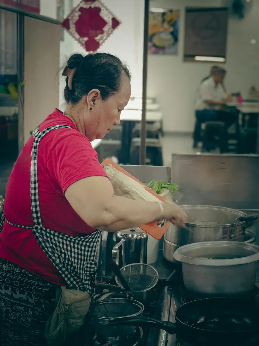 Artisane d'une quarantaine d'années en tablier dans un petit atelier alimentaire en inox