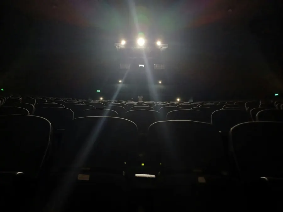 Salle de spectacle vide, projecteurs allumés au-dessus des fauteuils dans la pénombre