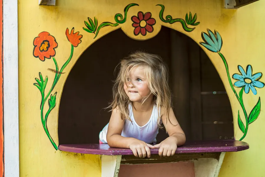 Petite fille souriante à la fenêtre peinte d'un castelet