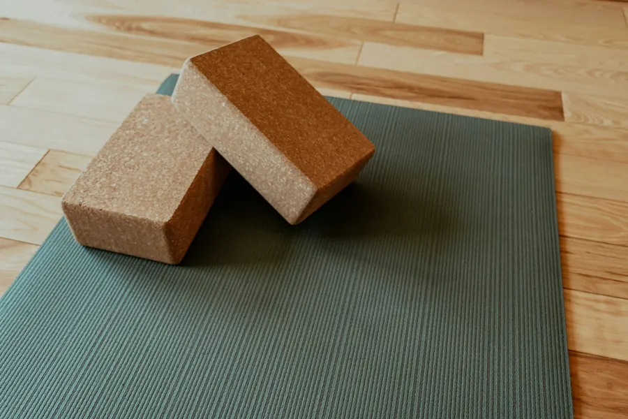 Blocs de yoga en liège posés sur un tapis, sans sangles ni couvertures visibles