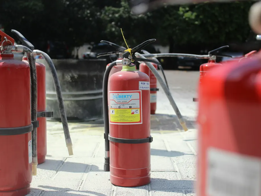 Plusieurs extincteurs rouges posés côte à côte en extérieur