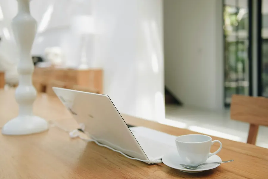 Ordinateur portable sur une table en bois, tasse de thé, pièce calme, écran éteint