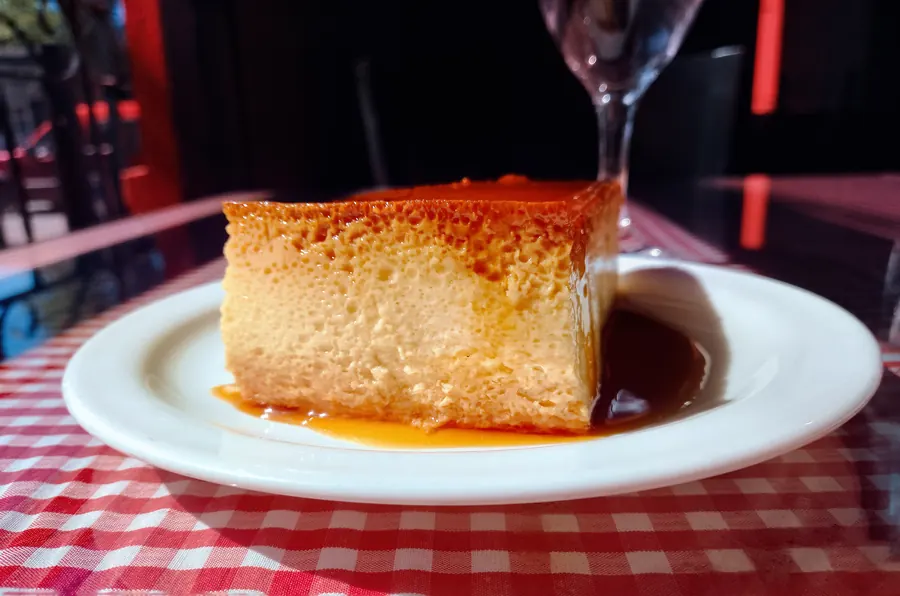 Part de flan à la crème, nappée de caramel, assiette blanche