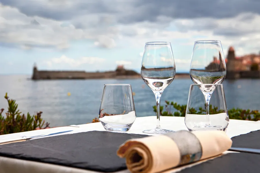 Terrasse dressée face à un port normand, bateaux à quai, lumière de fin de journée