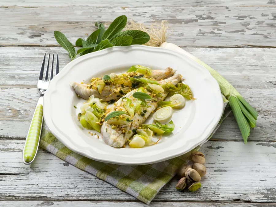 Filet de lieu jaune au beurre blanc, légumes du moment, assiette blanche sur table en bois