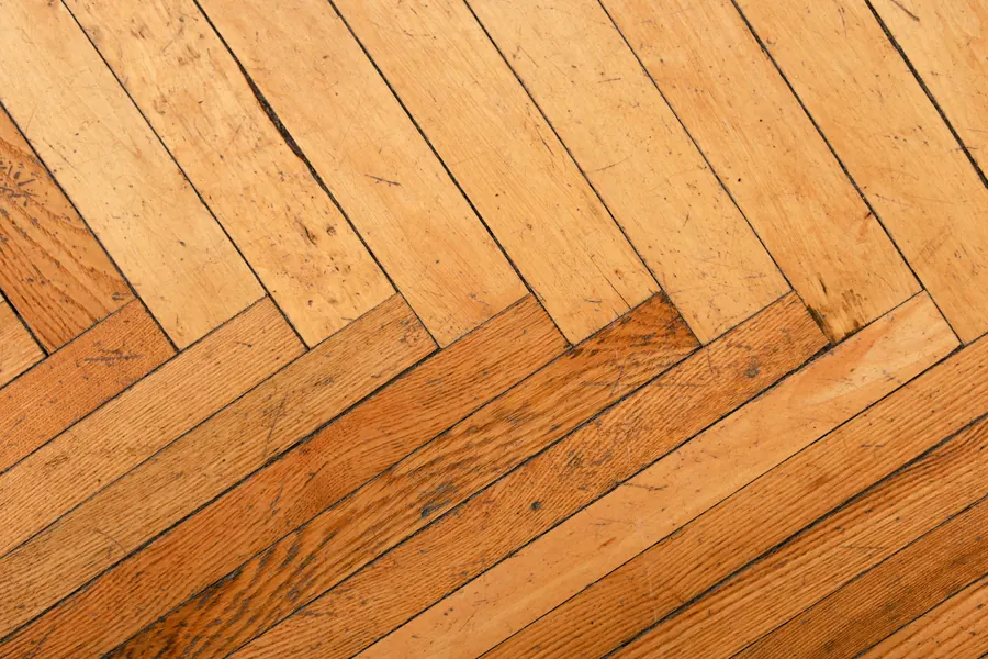 Gros plan sur un parquet en chevrons de bois blond