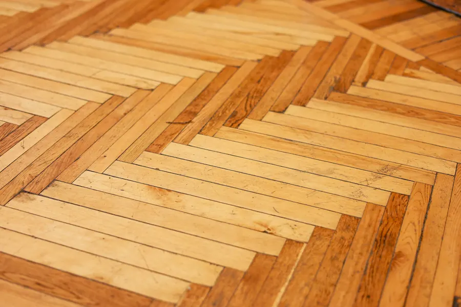 Ponçage d'un ancien parquet point de Hongrie, moitié poncée, moitié encore sombre