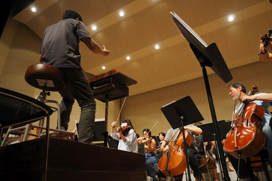 Chef d'orchestre vu de dos qui dirige un ensemble en répétition