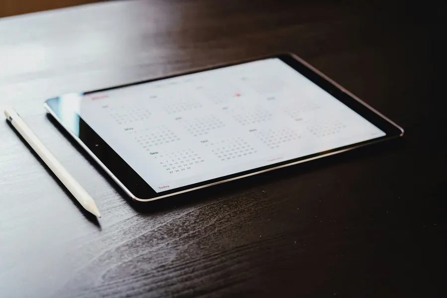 Tablette affichant une application de calendrier, posée sur une table