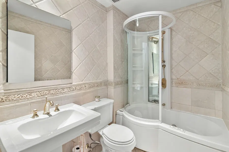 Salle de bain beige avec baignoire d'angle et douche vitrée