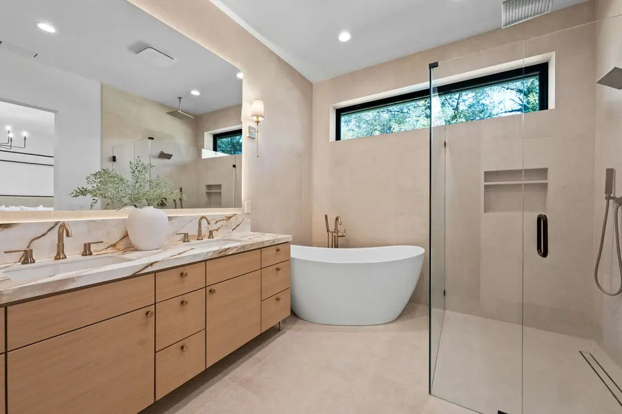Salle de bain claire avec baignoire, douche vitrée et grande fenêtre