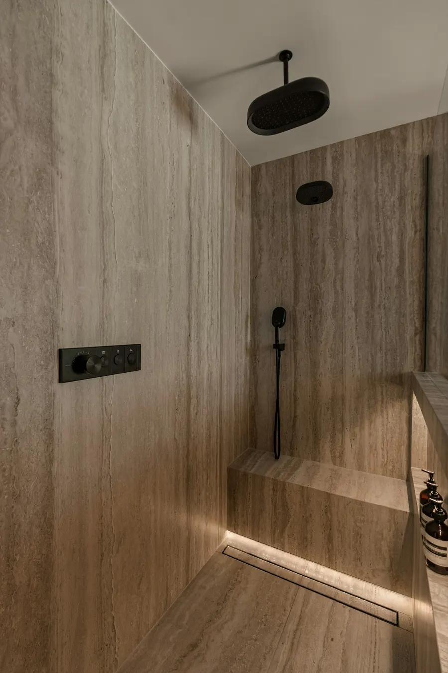 Douche à l'italienne en travertin beige avec robinetterie noire