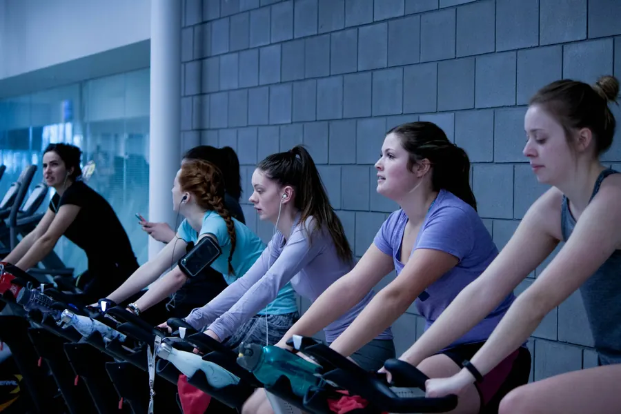 Cours de vélo en salle le soir, coach souriant, participants ordinaires