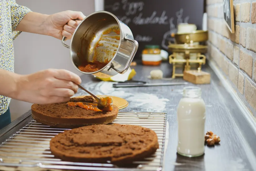Pâtissière qui assemble un gâteau dans une cuisine de boulangerie
