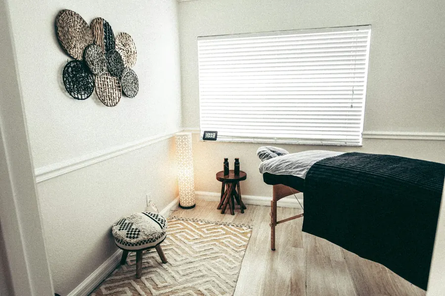 Cabine de massage calme, table couverte d'un drap sombre, lumière filtrée par un store