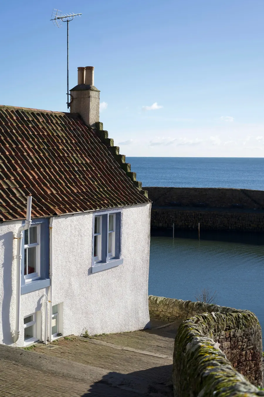 Maison blanche au bord de l'eau avec fenêtres à encadrement bleu clair