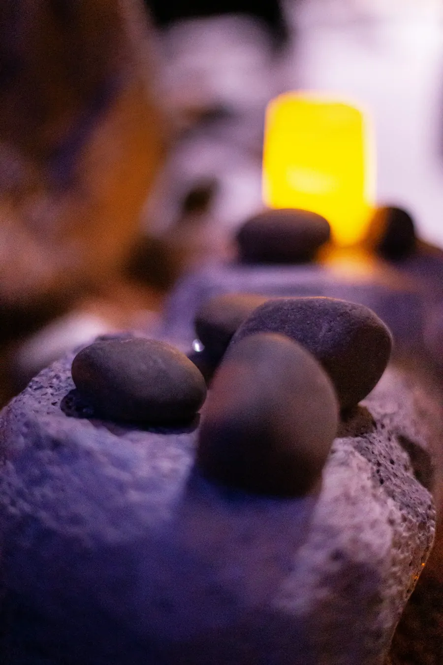Pierres de massage noires alignées, éclairage chaud, posées sur la pierre