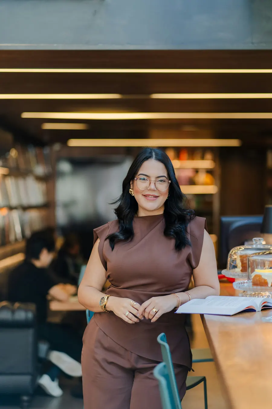 Jeune femme souriante dans un café avec une bibliothèque en arrière-plan