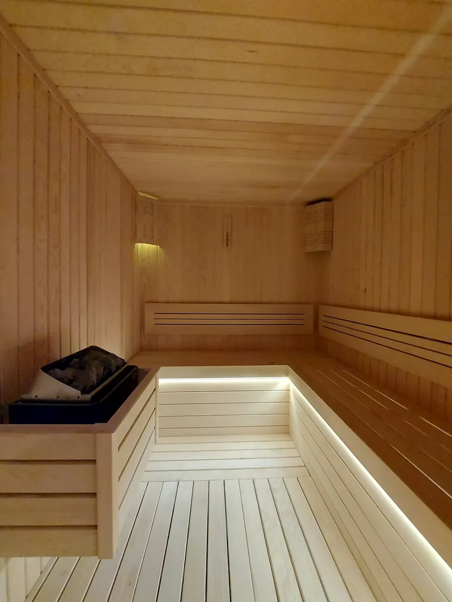 Sauna en bois clair, bancs, lumière chaude