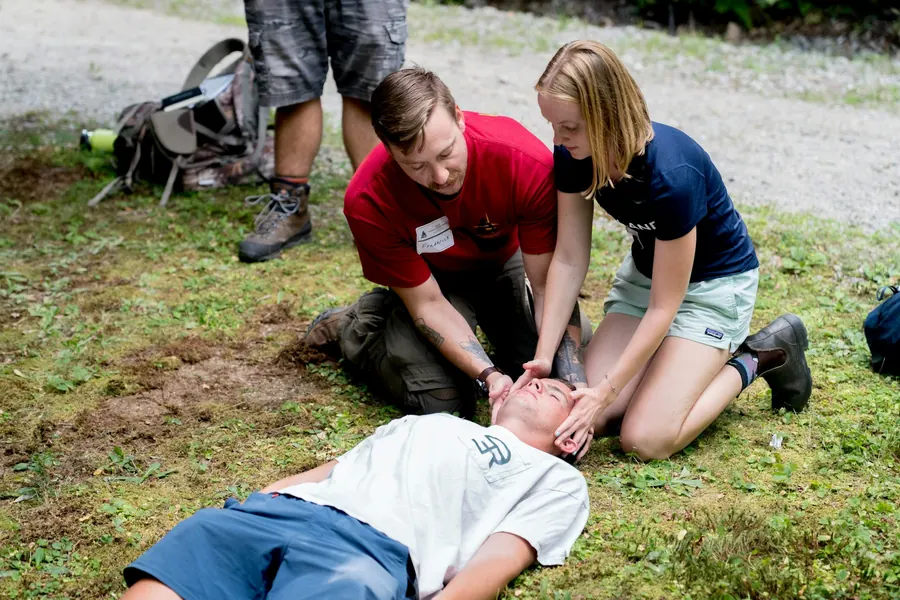 Formateur agenouillé qui enseigne les gestes de premiers secours en plein air