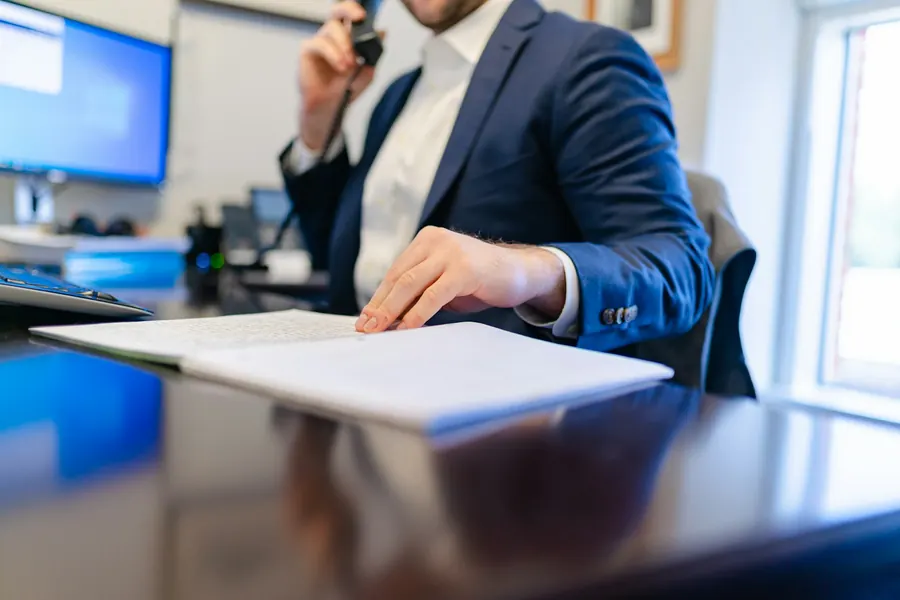 Juriste au téléphone, dossier ouvert et ordinateur, bureau simple