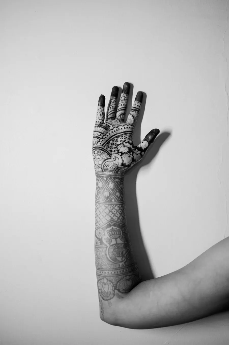 Main et avant-bras couverts d'un tatouage ornemental noir