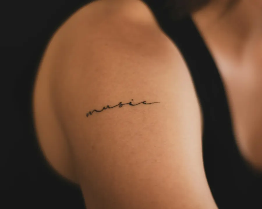 Petit lettrage manuscrit tatoué sur le haut du bras