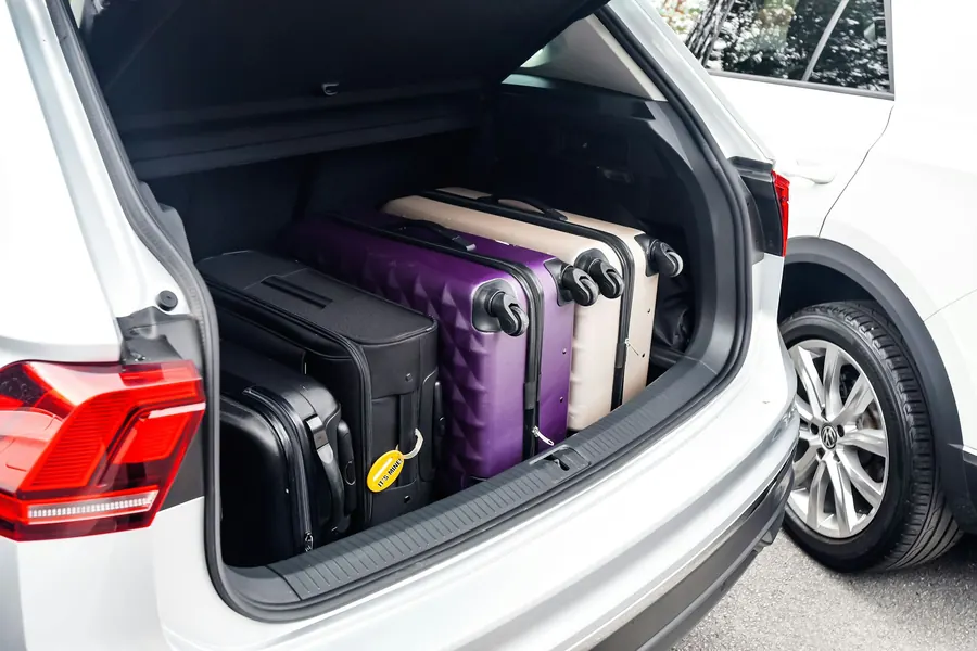 Coffre de voiture rempli de valises, sans chauffeur ni gare visible