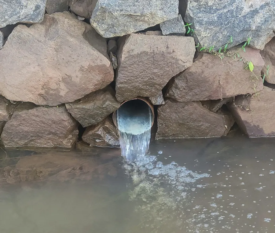 Drain agricole et gravier au pied d'un mur de maison en pierre