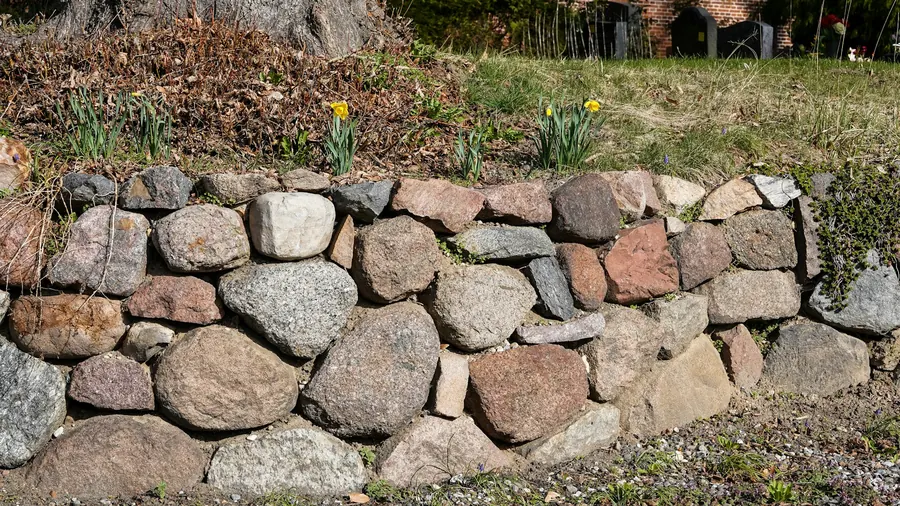 Mur de gros blocs de granit en talus, jardin en pente