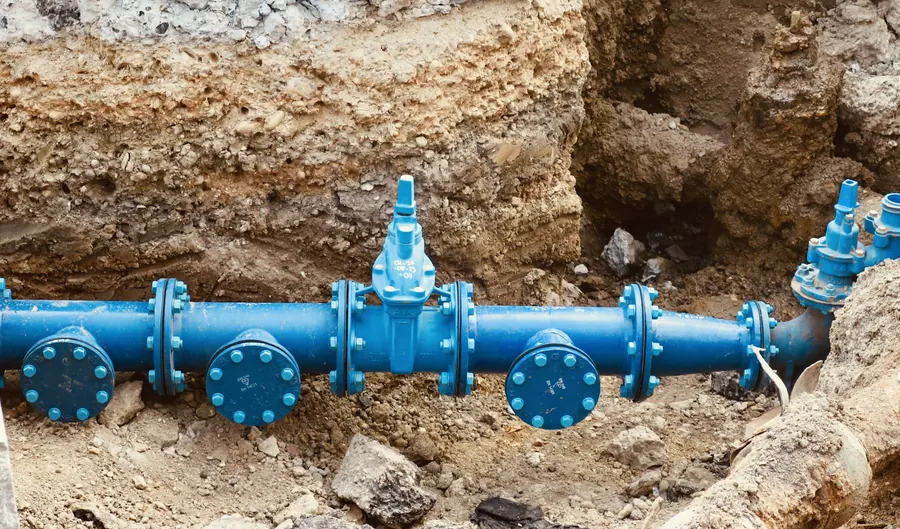 Vanne et tuyau bleu installés dans une tranchée de terre